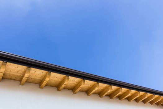 Low angle view of new house with wooden roof and gutter against clear blue sky