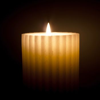 Isolated burning candle on dark background