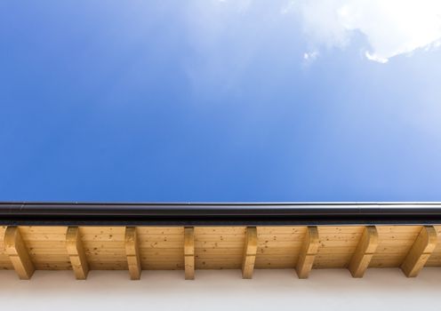 Low angle view of new house with wooden roof and gutter against clear blue sky