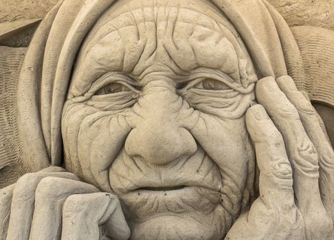 Portrait of a old and wrinkled peasant, carved in the sand.