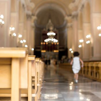 A little girl runs to church, heading for the altar. Defocused blurry background.