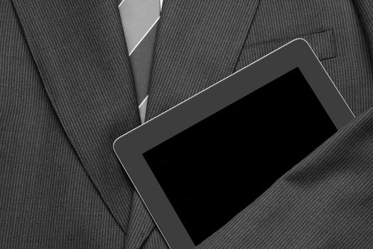 Closeup of a business jacket with white shirt and tie with one arm over a tablet computer. the empty suit is laid out and ready for the day. The screen is blank. Horizontal format. 
