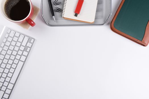 White desk shot from a high angle with keyboard, coffee, flash drive, and other office equipment.