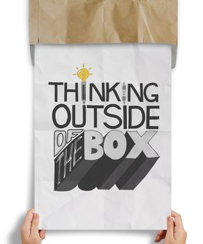 businessman hand showing design word THINKING OUTSIDE OF THE BOX on crumpled paper as concept