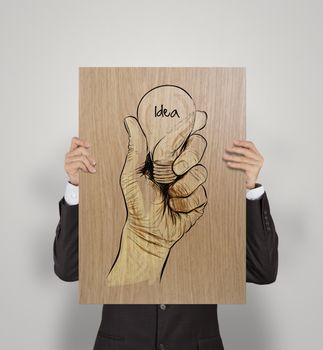 man showing poster of Hand drawn light bulb with IDEA word on wooden board as concept 