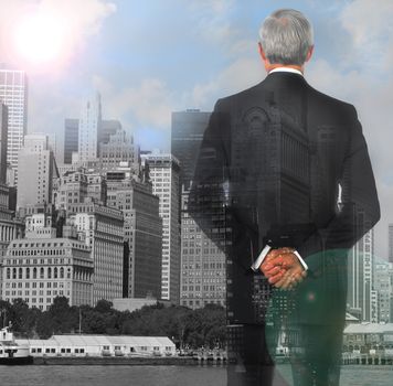 Businessman double exposure with his hands clasped behind his back with city background and lens flare.