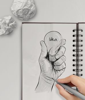 Hand drawn light bulb with IDEA word on note book as concept