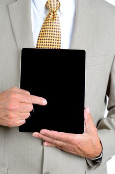 Closeup of a businessman in a suit pointing at the screen of a tablet computer. Man is unrecognizable, with tablet held in front of his torso.