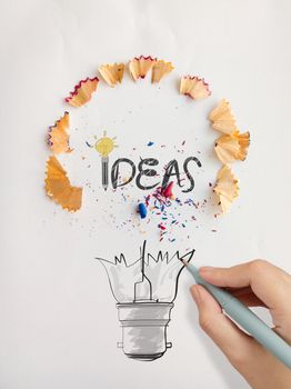 hand drawn light bulb word design IDEA with pencil saw dust on paper background as creative concept