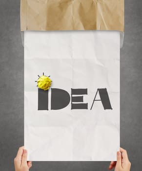 yellow crumpled paper on hand drawn IDEA on poster background as creative concept