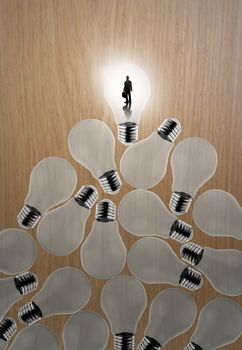 businessman standing at 3d growing light bulb standing out from the unlit incandescent bulbs as leadership concept