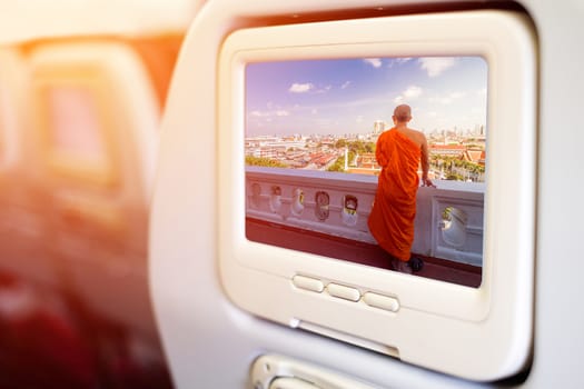 Aircraft monitor in front of passenger seat showing Unidentified buddhist monks in City view point at Golden moutain Temple, Thailand