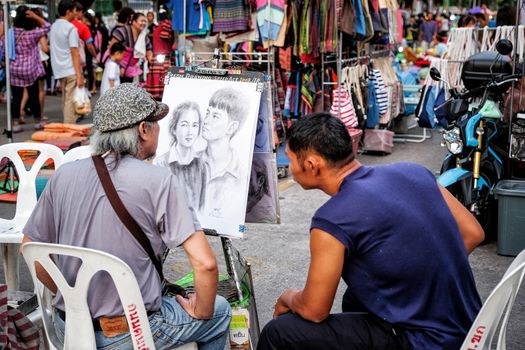 29 May 2016 : Artist street painter sketching a family portrait  on night Market street in KhonKaen Thailand at 29 May 2016