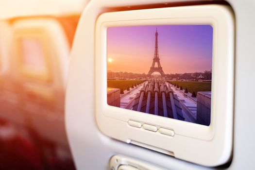 Aircraft monitor in front of passenger seat showing Eiffel Tower and fountain at Jardins du Trocadero at sunrise, Paris, France