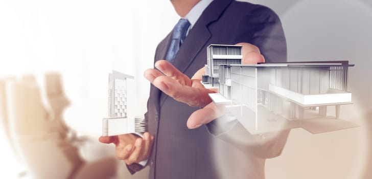 businessman hand presents house model on modern computer as development concept