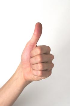 White hand doing a "thumb up" against a white background. Positivity, approval, success concept.