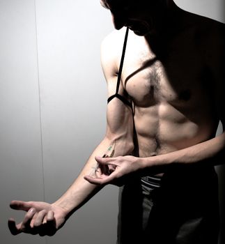Addicted man injecting intravenous drug. Dark studio shot.