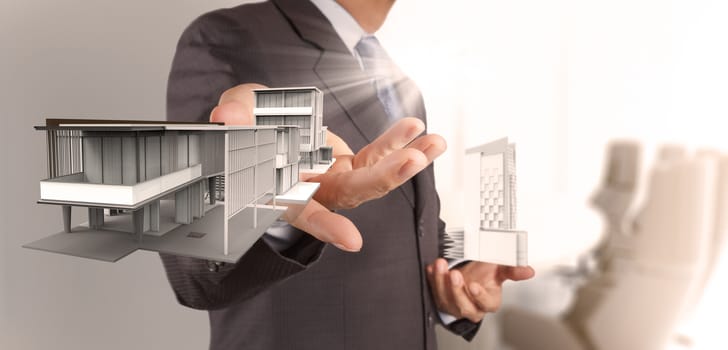 businessman hand presents house model on modern computer as delvelopment concept