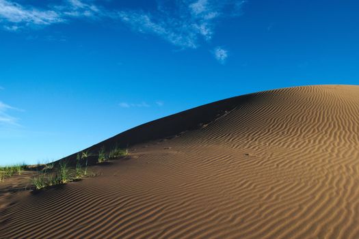 Large sand dune beneath a blue sky with clouds, in the desert of Lavalle, province of Mendoza, Argentina