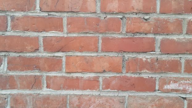 Closeup texture of red brick wall. A background of a weathered old exterior brick wall in the sunshine.