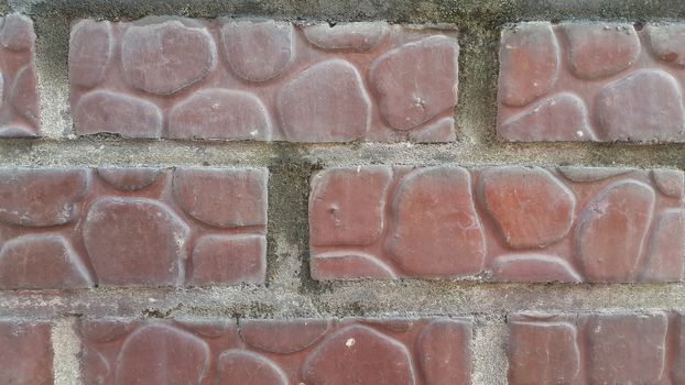 Closeup texture of red brick wall. A background of a weathered old exterior brick wall in the sunshine.