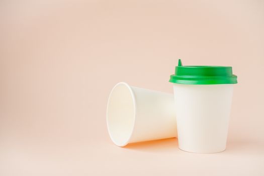 Disposable paper cups with a plastic lid on a light pink background. ecology, zero waste concept. copyspace.