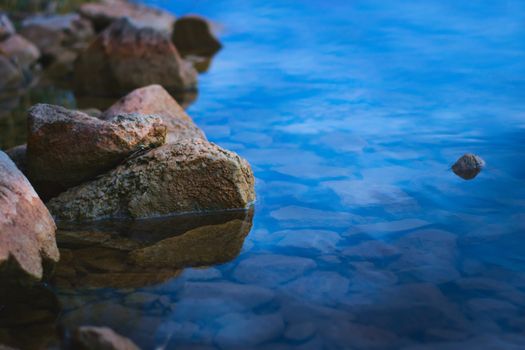 Natural stones on the shore of a lake at dusk. Tranquil scene, relaxing calm, zen meditation background.
