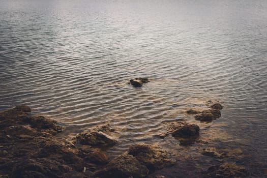 Rocky shore of lake La Florida, in San Luis, Argentina, on a dark, cloudy day.