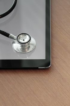 Stethoscope with digital tablet computer on wooden table and  background 