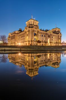 The famous Reichstag in Berlin at dawn reflects in the river Spree