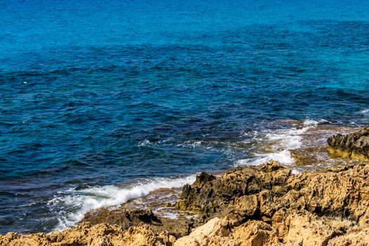 Mediterranean coast on a sunny day with rocks and blue waves.