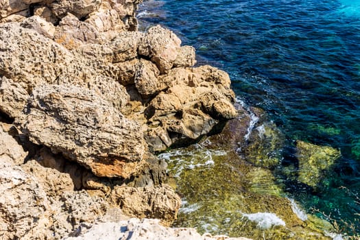 Mediterranean coast on a sunny day with rocks and blue waves.