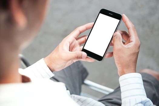 Cropped shot view of man hands holding smart phone with blank copy space screen for your text message or information content, female reading text message on cell telephone during in urban setting. 