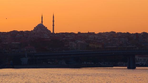 Hagia Sophia, the most important tourist attraction of Istanbul, Turkey, silhouetted against the ochre sunset sky from across the Bosphorus.