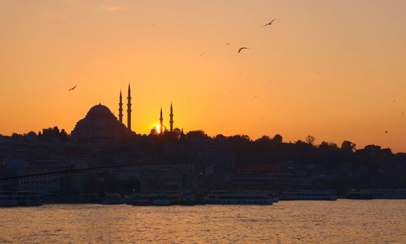 Hagia Sophia, the most important tourist attraction of Istanbul, Turkey, silhouetted against the ochre sunset sky from across the Bosphorus.