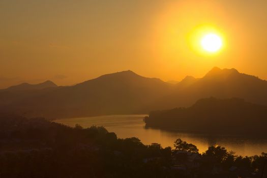 Sunset over hazy mountains by the Mekong river. View from Mount Phou Si, in Luang Prabang, Laos.
