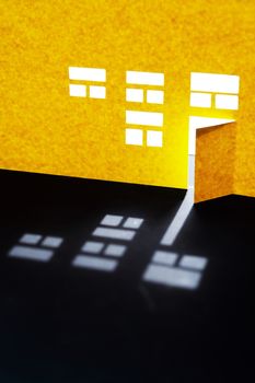 Composition cutting from paper. Yellow house with glowing windows and open door