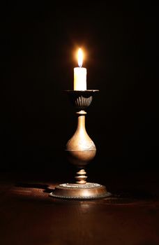 Elegant brass candlestick with lighting candle on dark background