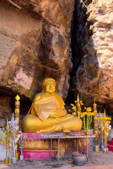 Golden statue of a buddhist monk on a crevice of the mountain at Mount Phou Si, in Luang Prabang, Laos.