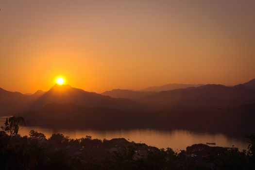 Glorious sunset over hazy mountains by the Mekong river. View from Mount Phou Si, in Luang Prabang, Laos.