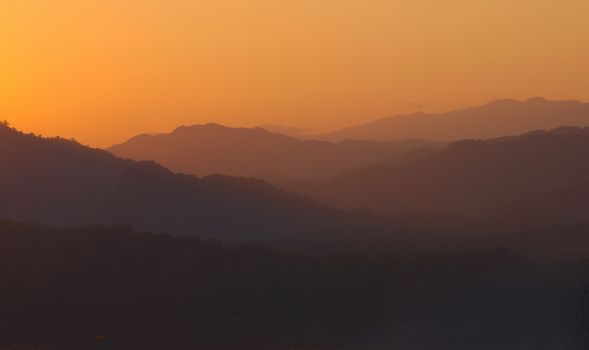 Orange sky over hazy mountains around Luang Prabang, Laos. View from the top of Mount Phou Si.