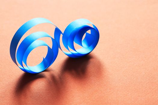 Two blue spirals made from paper on red background