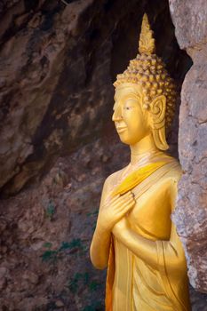 Golden statue of Buddha on a crevice of the rock at Mount Phou Si, in Luang Prabang, Laos.