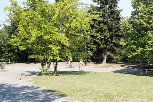 people walk in a city park on a summer sunny day.