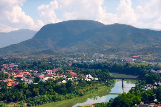 Town of Luang Prabang and Nam Khan river, in Laos. Lush jungle on the mountains can be seen on the background.