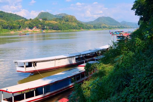 Long boats and barges sailing on the Mekong River near Luang Prabang, Laos.