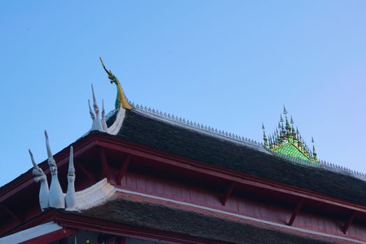 Buddhist temple of Wat Wisunarat in Luang Prabang, Laos. Architectural detail of the Naga serpents on the soffit and glass mosaic ornament on top.