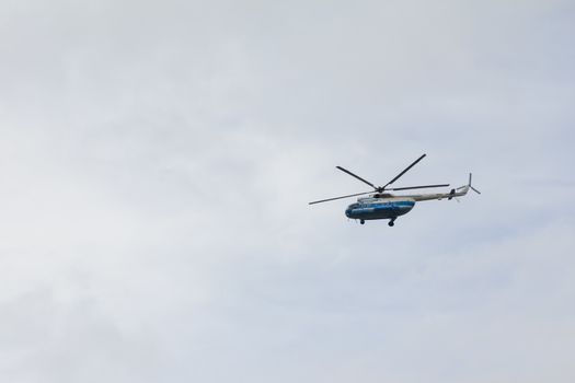 Helicopter high flying at the gray sky, telephoto shot