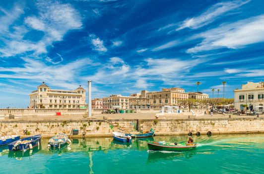 A motorboat sailing along the canal in Ortygia. Cityscape of the famous Sicilian town, Italy