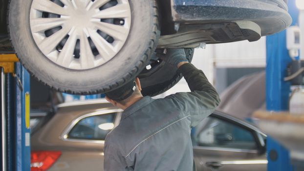 Mechanic working on a tire service on the lift in a service station, close up